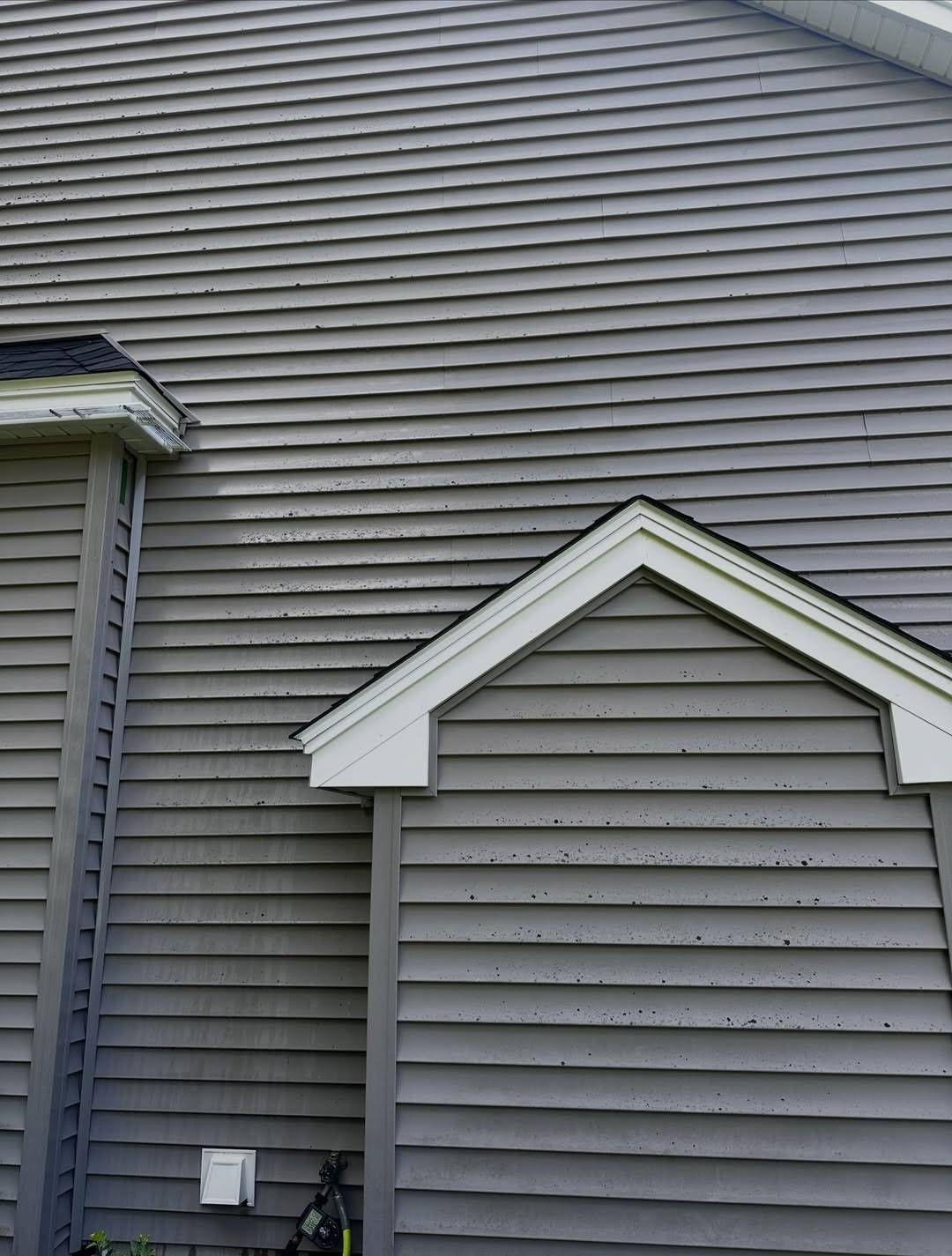 Before: Grey vinyl siding and a small gable bump-out dotted with black spots