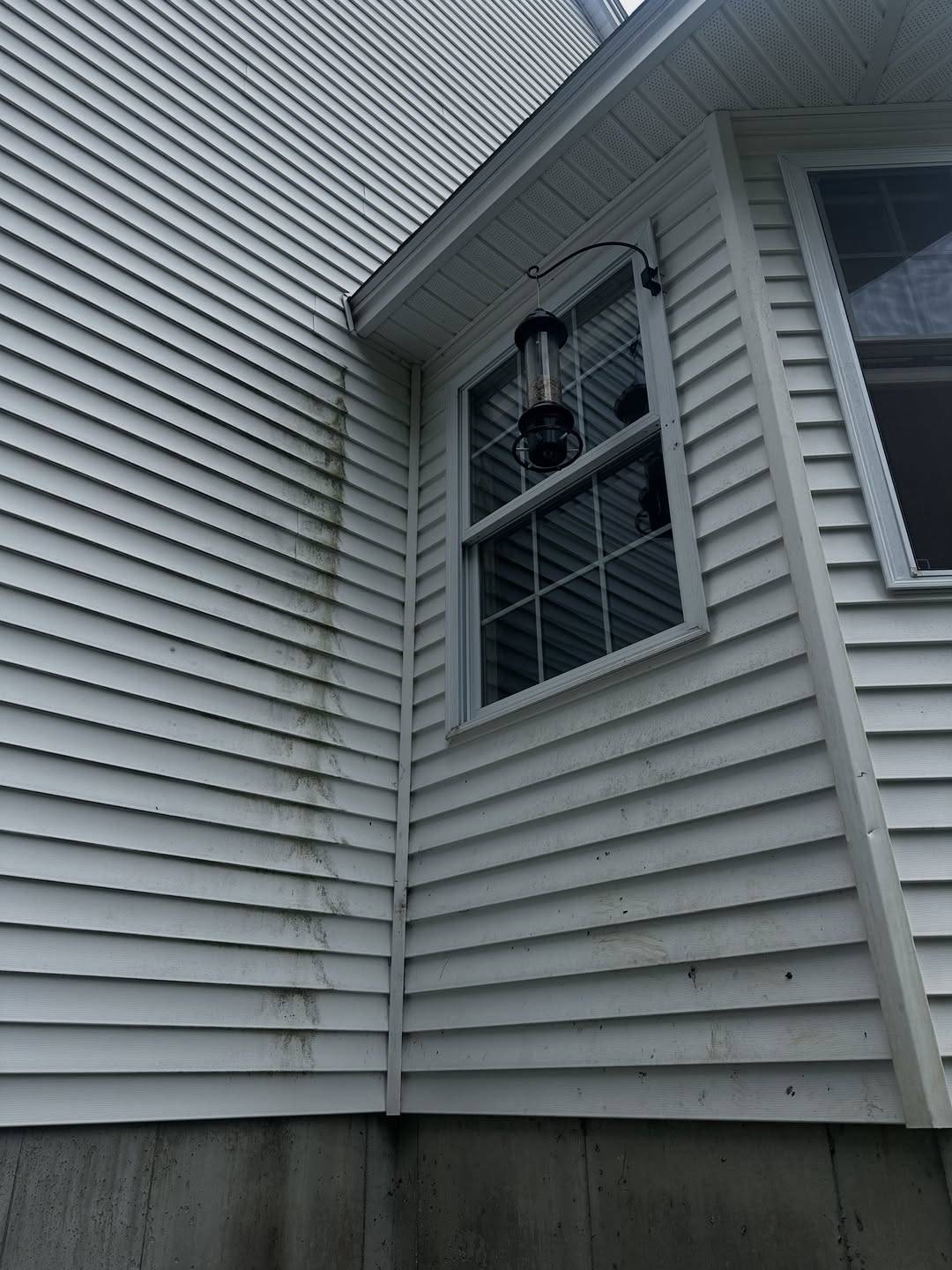 Before: White siding with dark streaks running down from a window corner